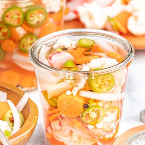 Mixed vegetables in a glass jar with liquid.