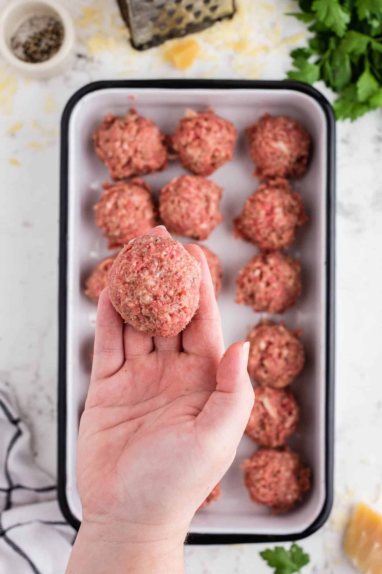 Round uncooked meatball in a hand.