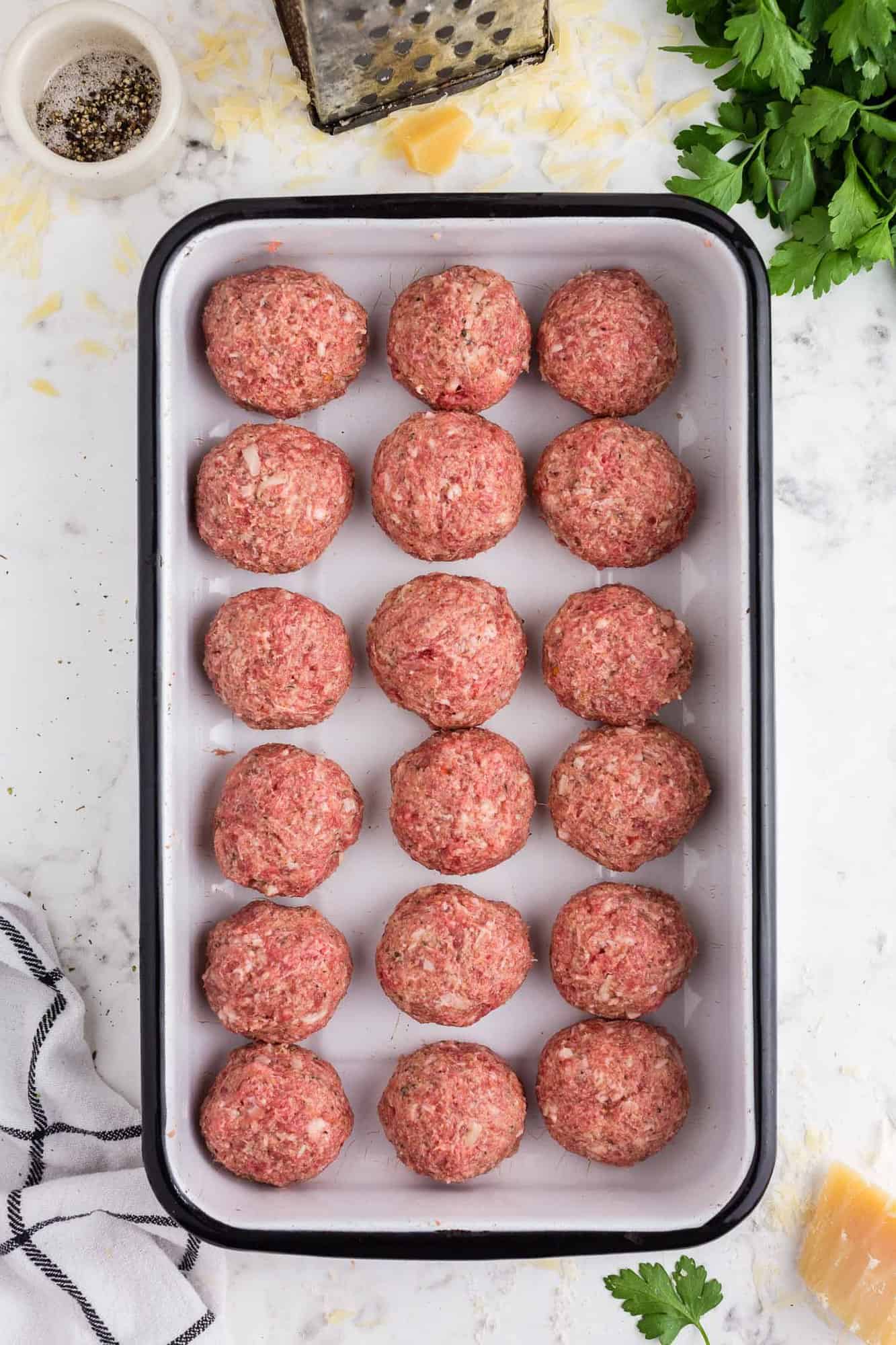 Overhead view of uncooked meatballs in a pan.