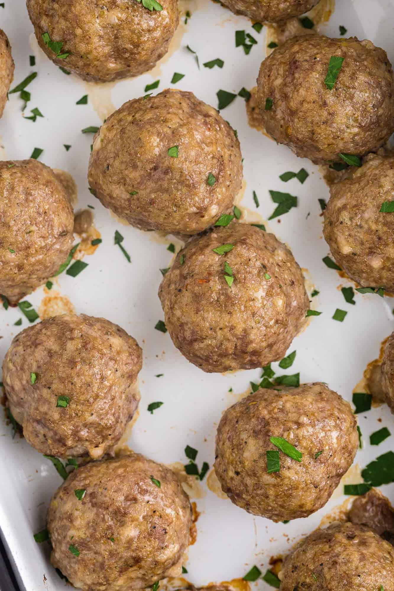 Overhead view of baked meatballs without sauce, sprinkled with parsley.