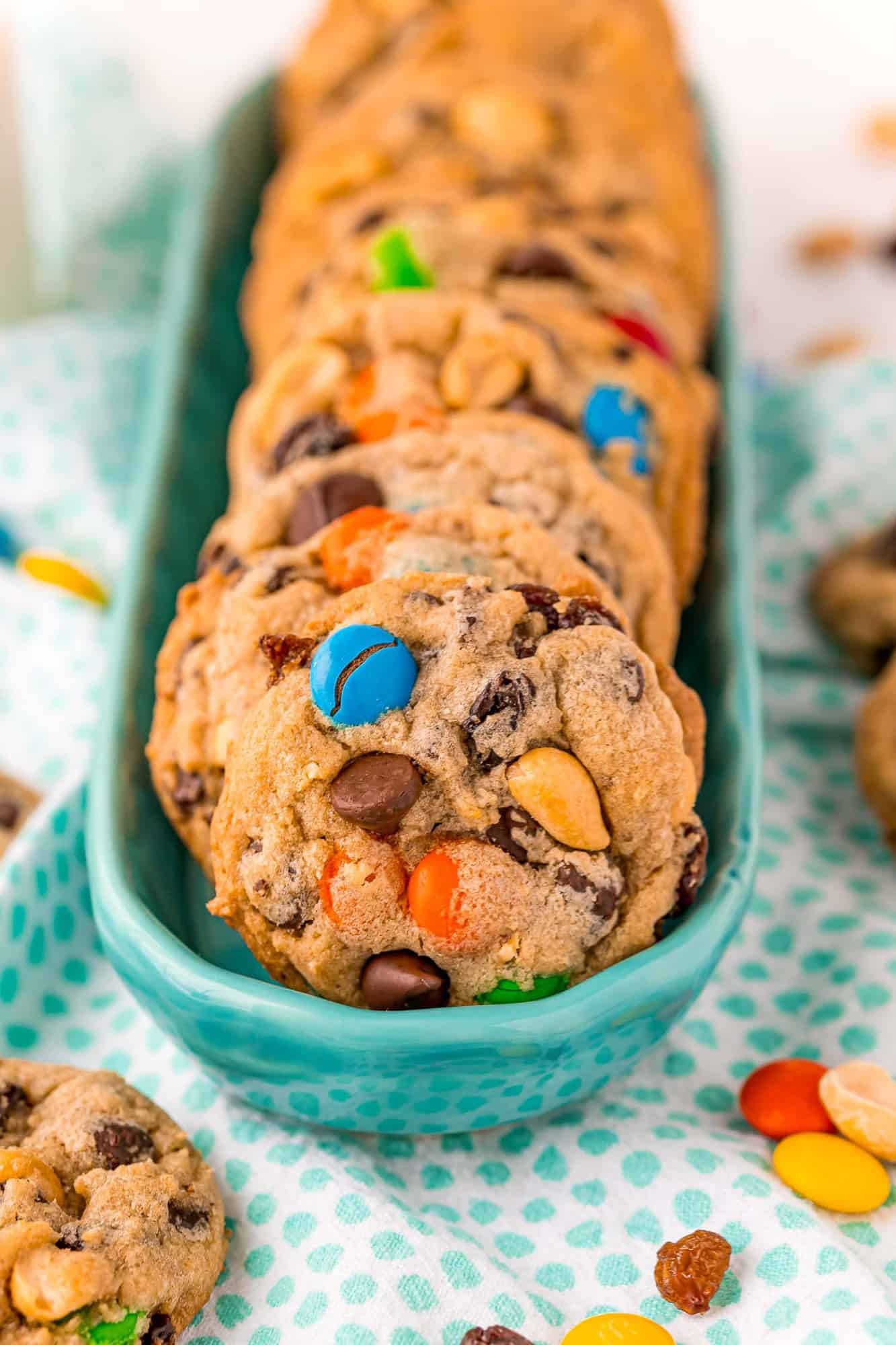 Trail mix cookies in a long narrow blue bowl.