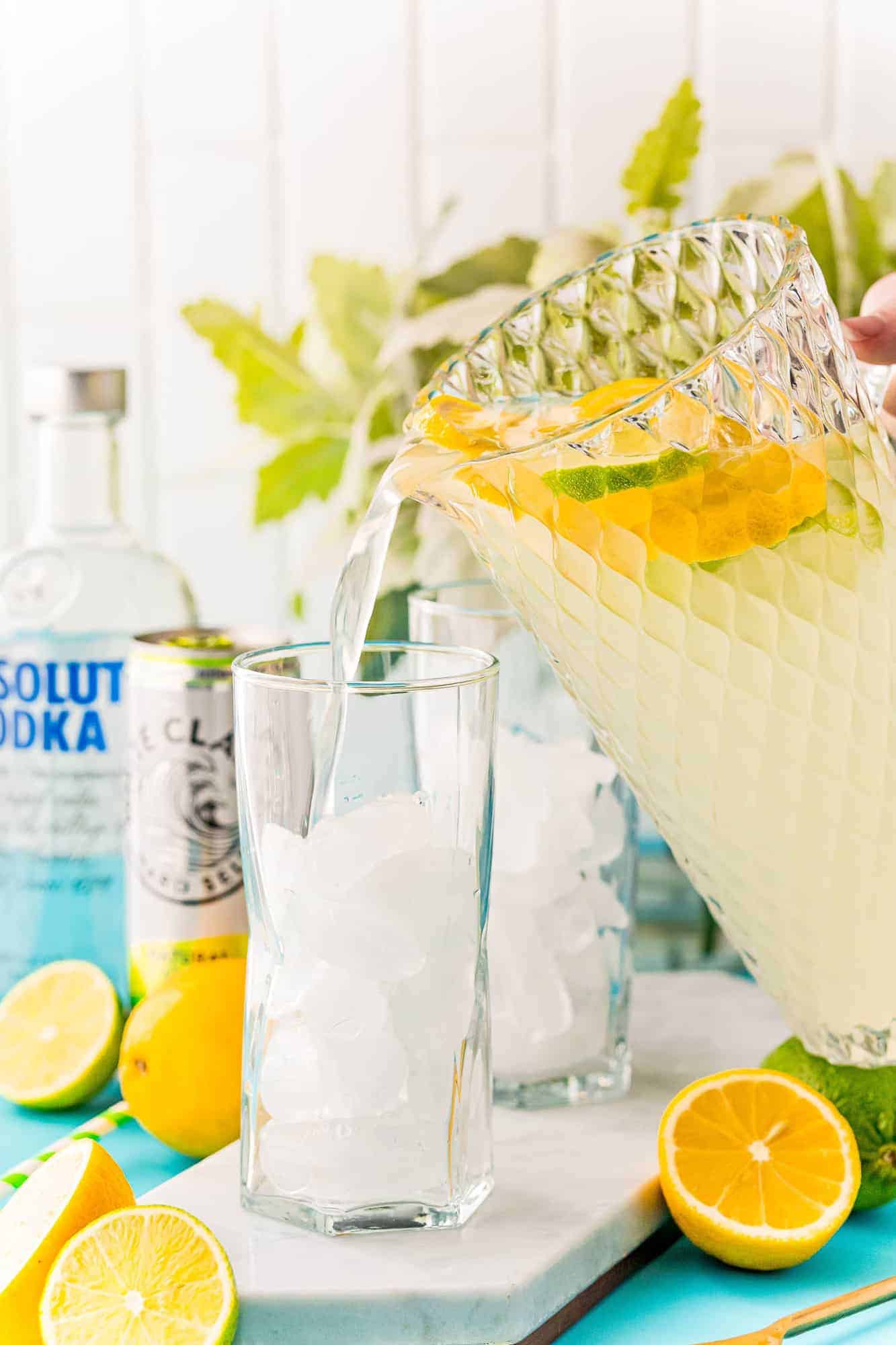 Lemonade being poured into a glass from a large glass pitcher.