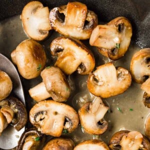 Cooked mushrooms in a pan with butter wine sauce.