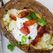 Potato filled with sour cream, onion, and bacon, text overlay reads "air fryer baked potatoes, rachelcooks.com"