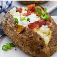 Potato filled with sour cream, onion, and bacon, text overlay reads "air fryer baked potatoes, rachelcooks.com"