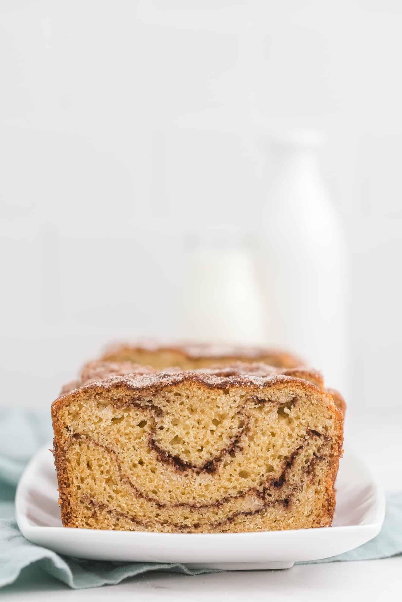 Shot of sliced loaf of quick bread with a glass bottle of milk in the background.