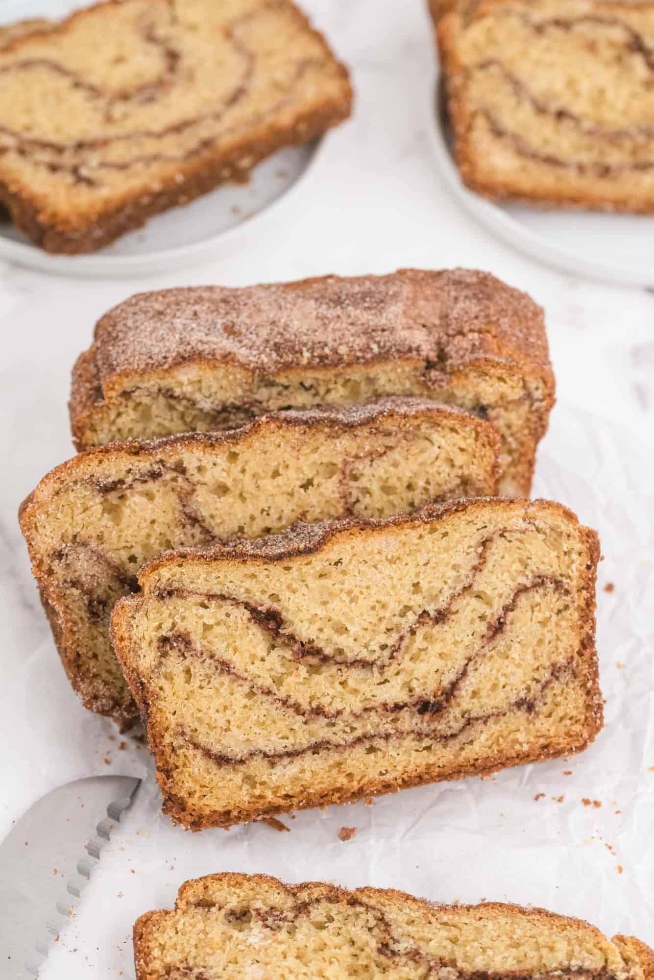 Sliced cinnamon swirl quick bread on a white background.