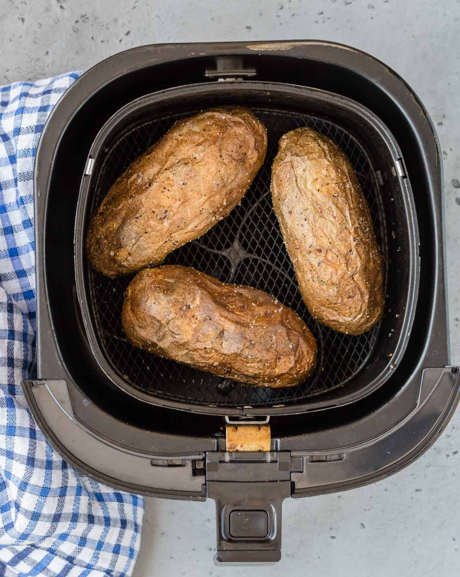 Overhead view of baked potatoes in an air fryer.