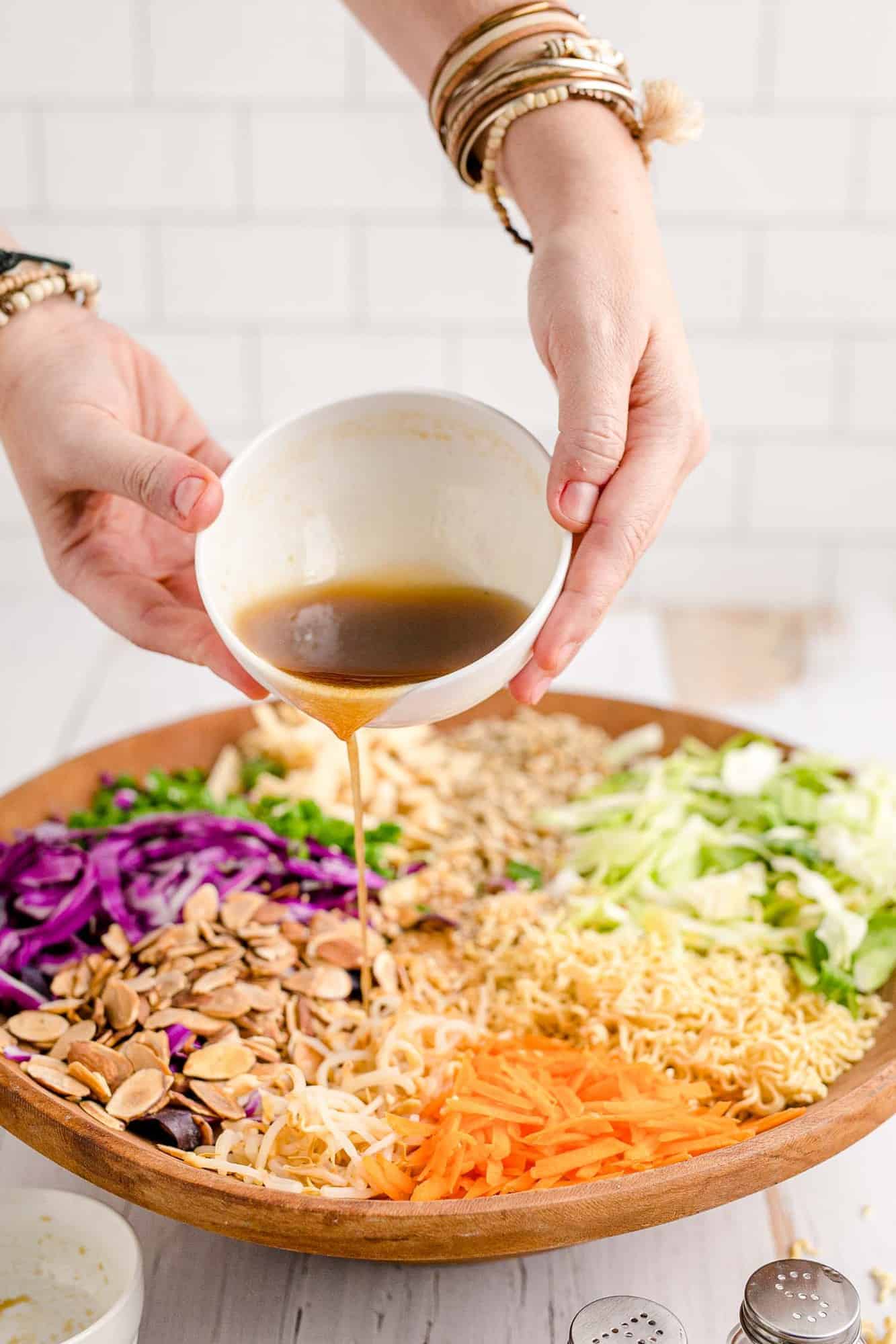 Dressing being poured on large salad.