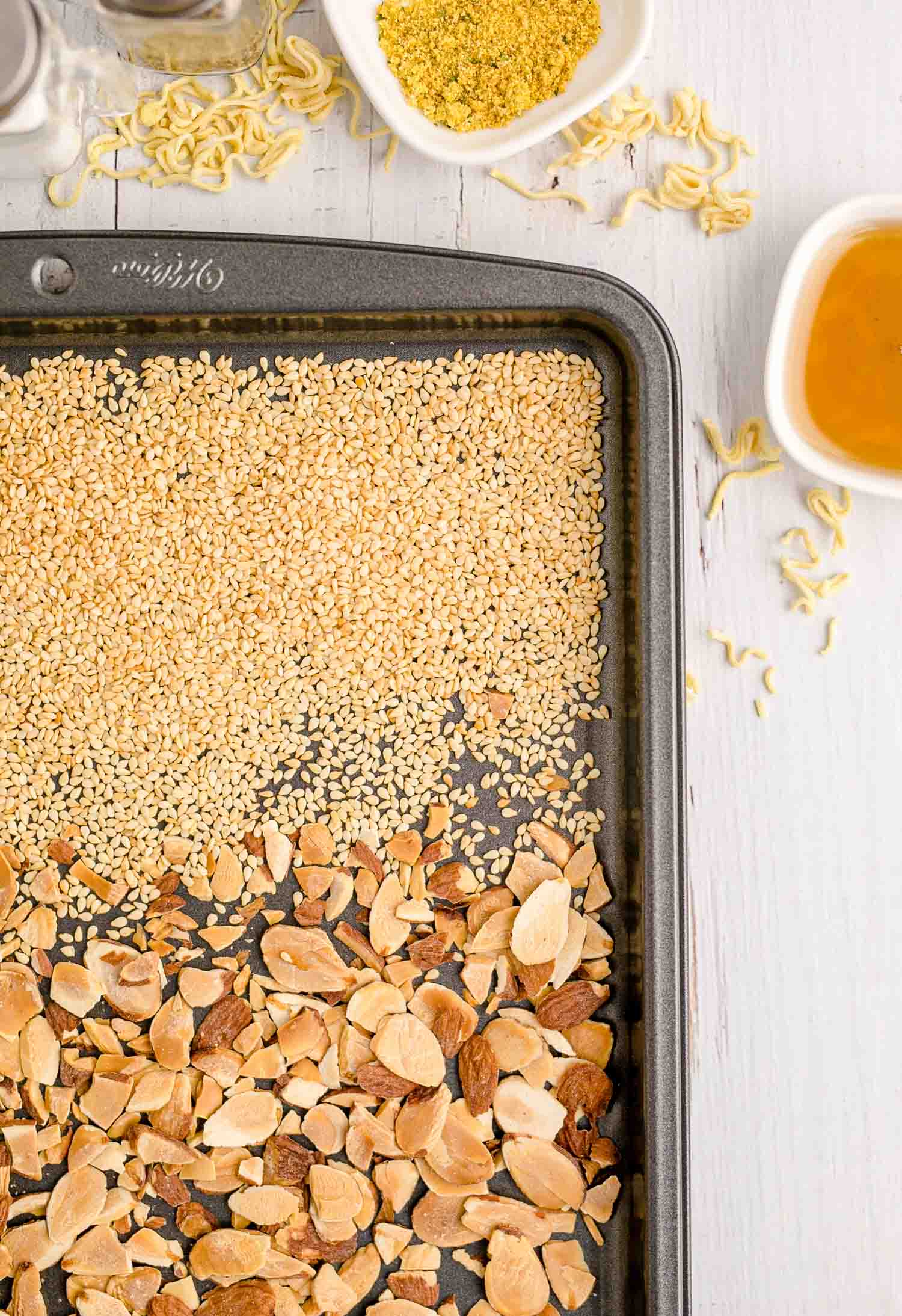 Toasted almonds and sesame seeds on a sheet pan.