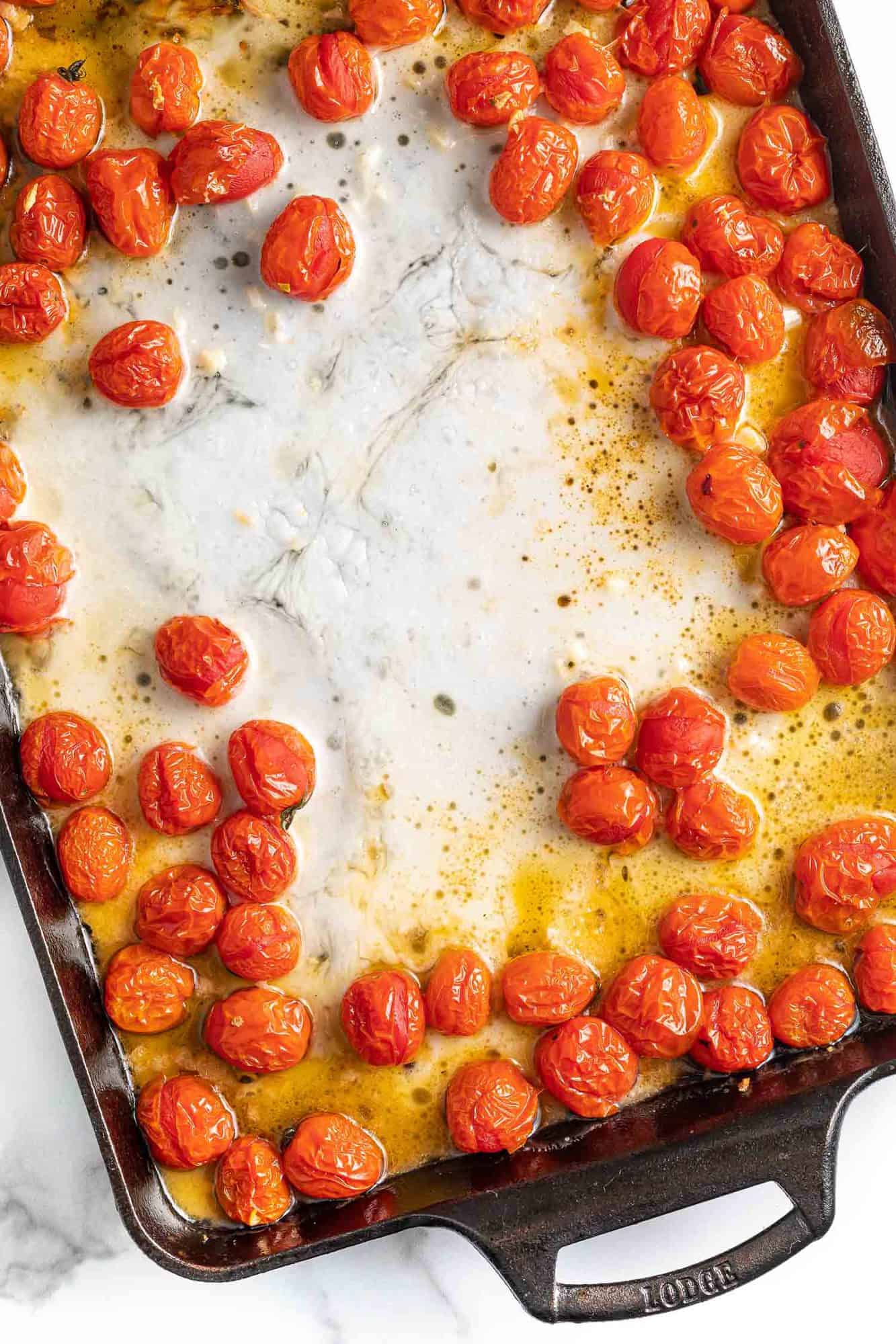 Melted feta and roasted tomatoes in a baking dish.