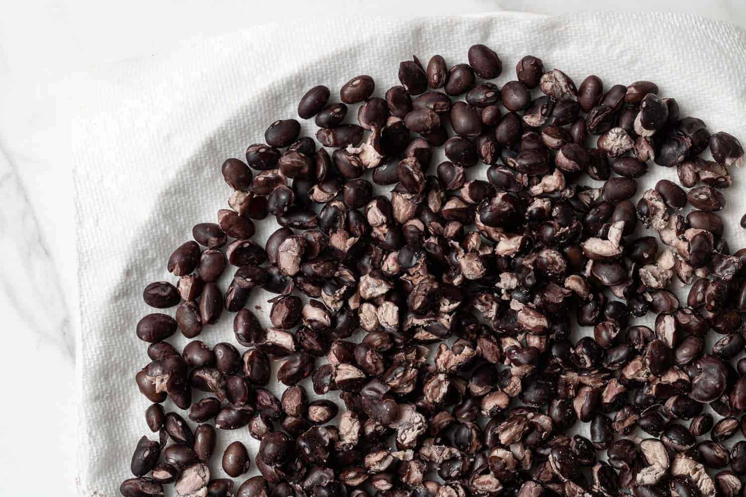 Black beans on a paper towel-lined white plate.