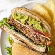 Black bean burger on a plate with chips, cut in half.