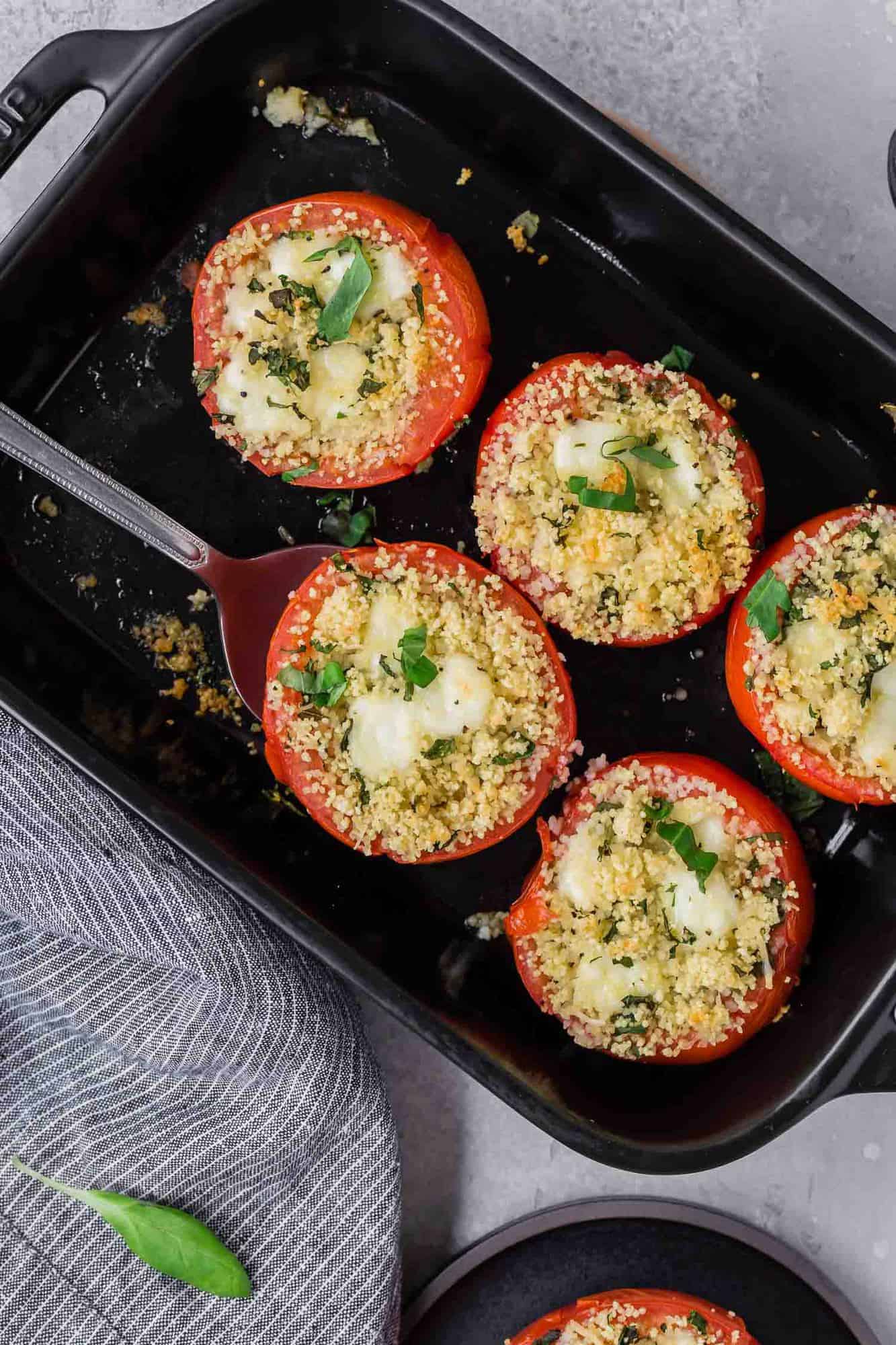 Overhead view of black baking dish with five stuffed tomatoes in it.