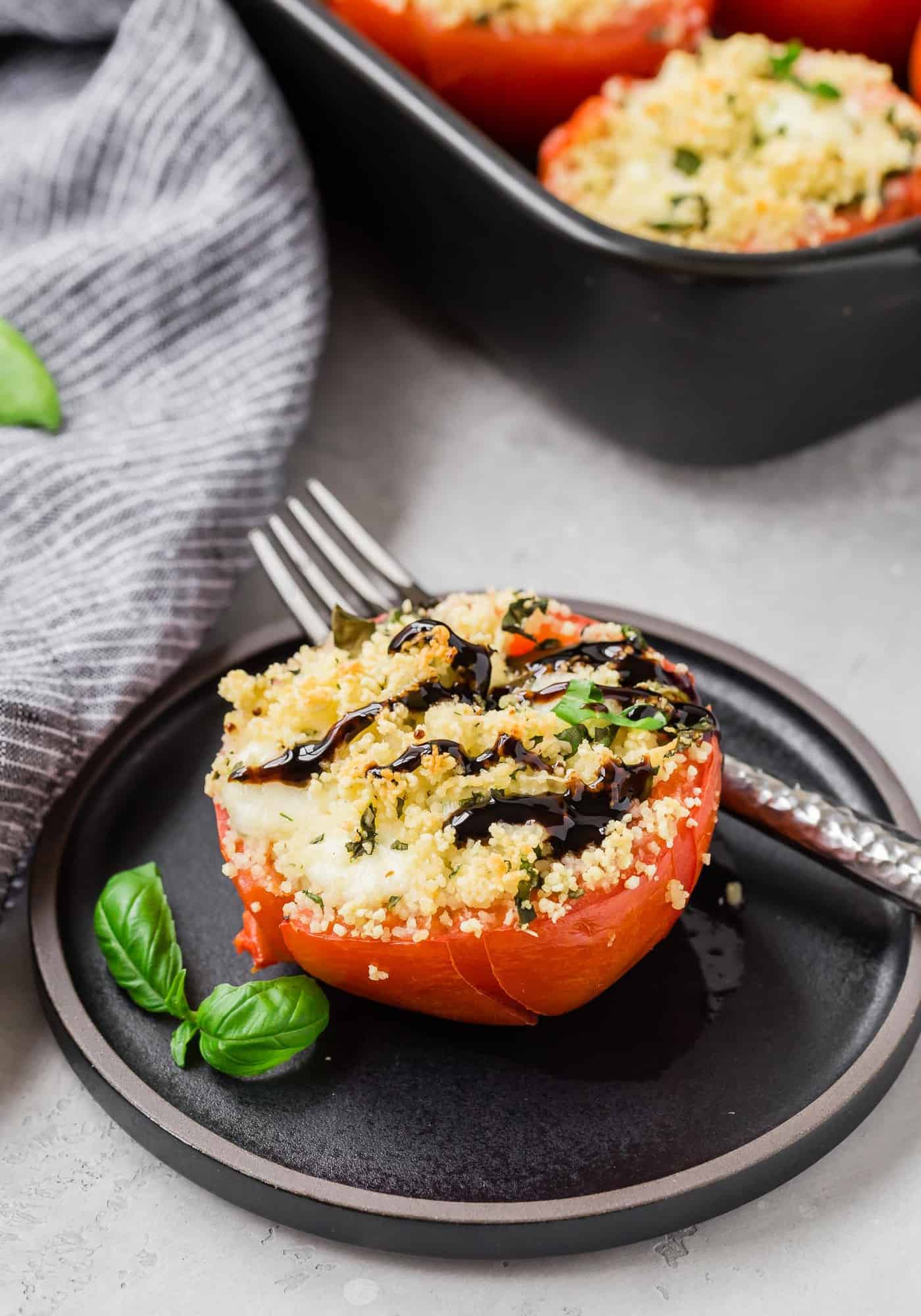 Stuffed tomato on a plate, drizzled with balsamic glaze.