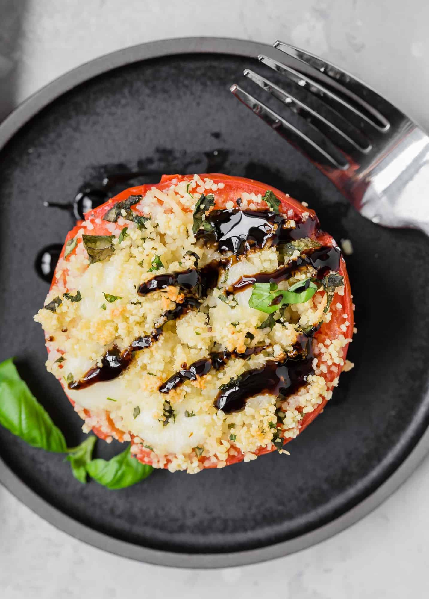 Overhead view of a tomato stuffed with couscous, mozzarella, and fresh basil.