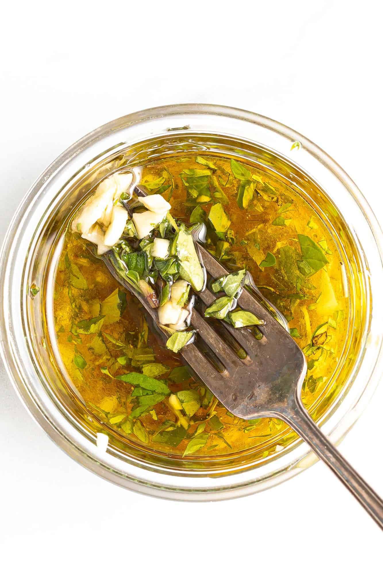 Dressing in a jar with a fork showing some ingredients.