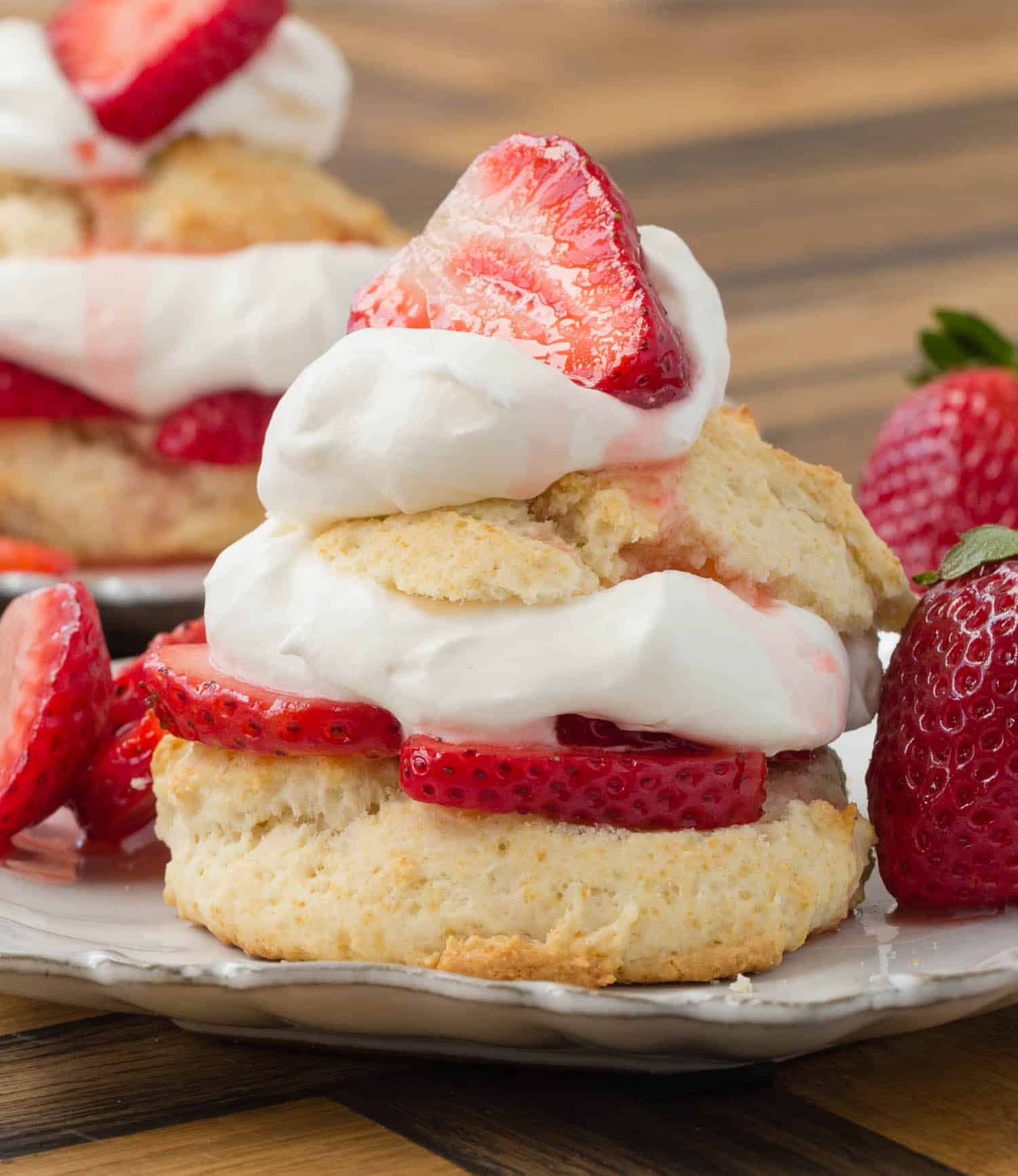 Straight-on view of a shortcake split in half and filled with whipped cream and sliced strawberries.