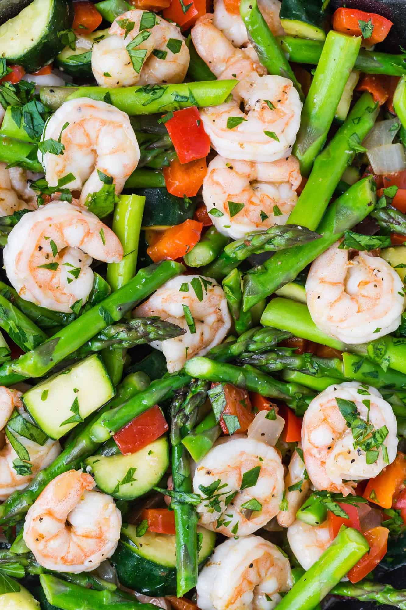 Close up view of a shrimp stir fry with asparagus, zucchini, and red bell peppers.