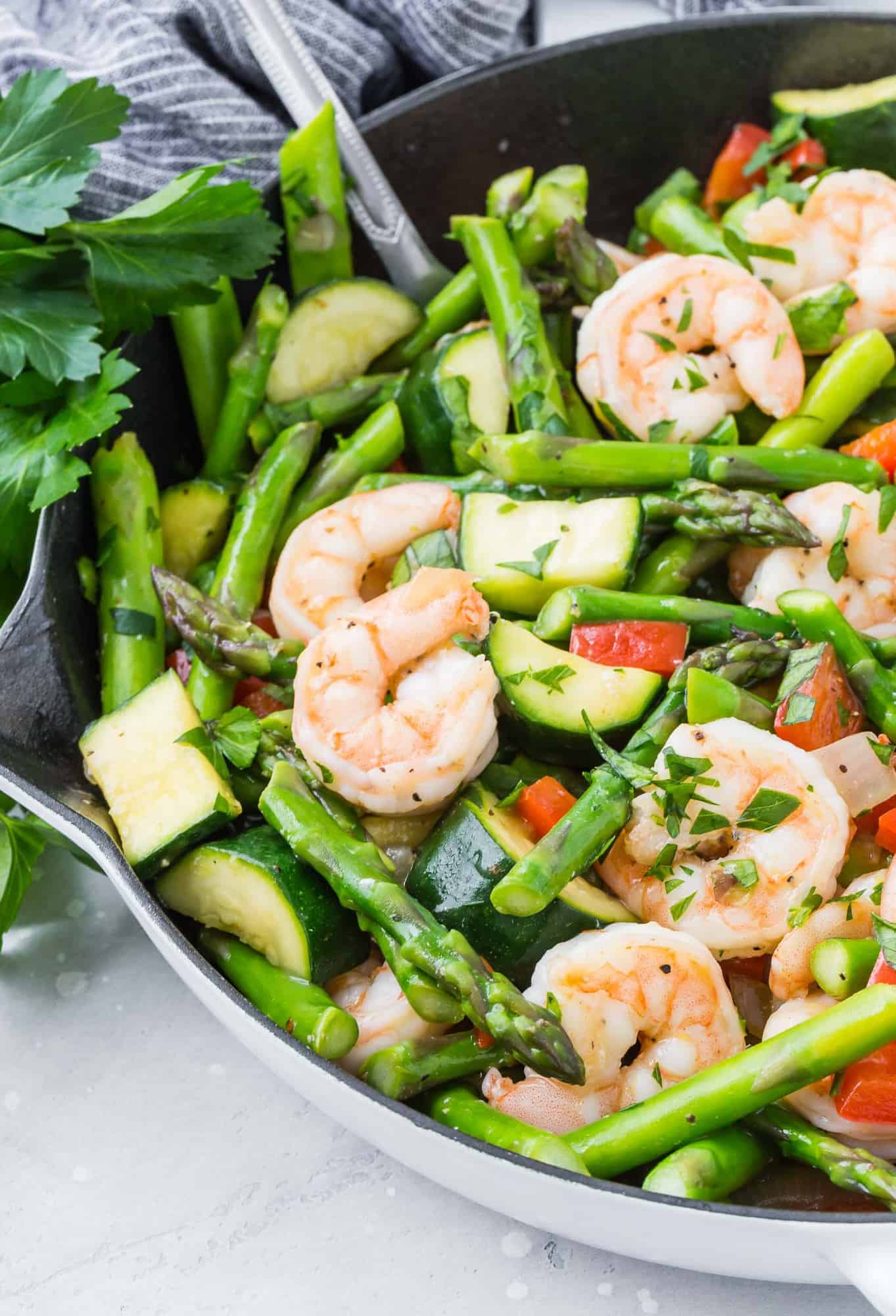 Shrimp and vegetables in a white skillet. 