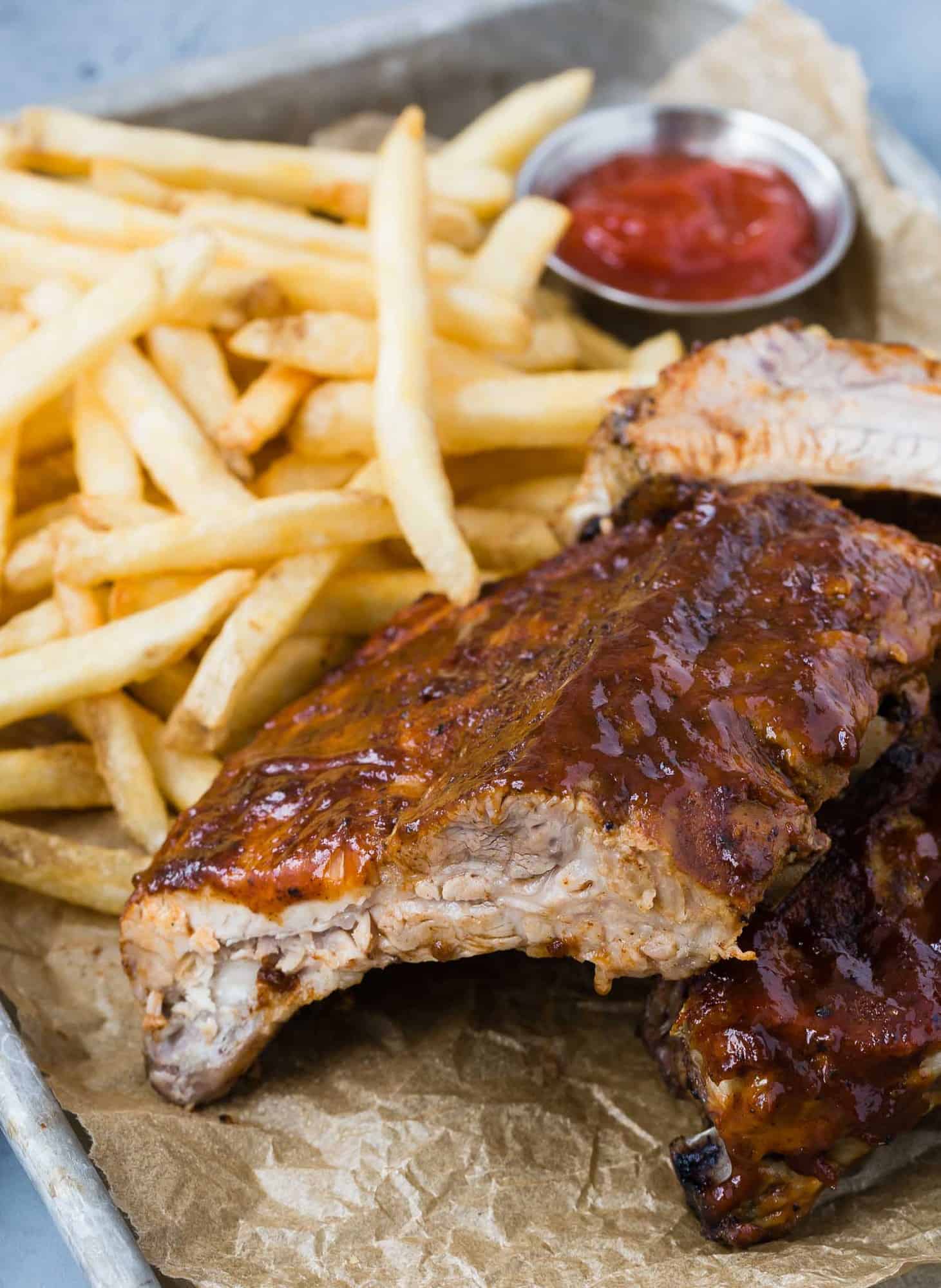 Close up view of bbq ribs with fries and ketchup.