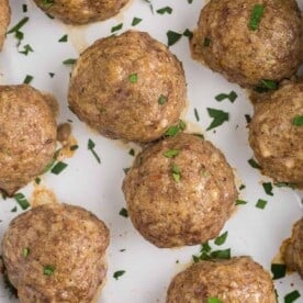 Overhead view of baked meatballs without sauce, sprinkled with parsley.