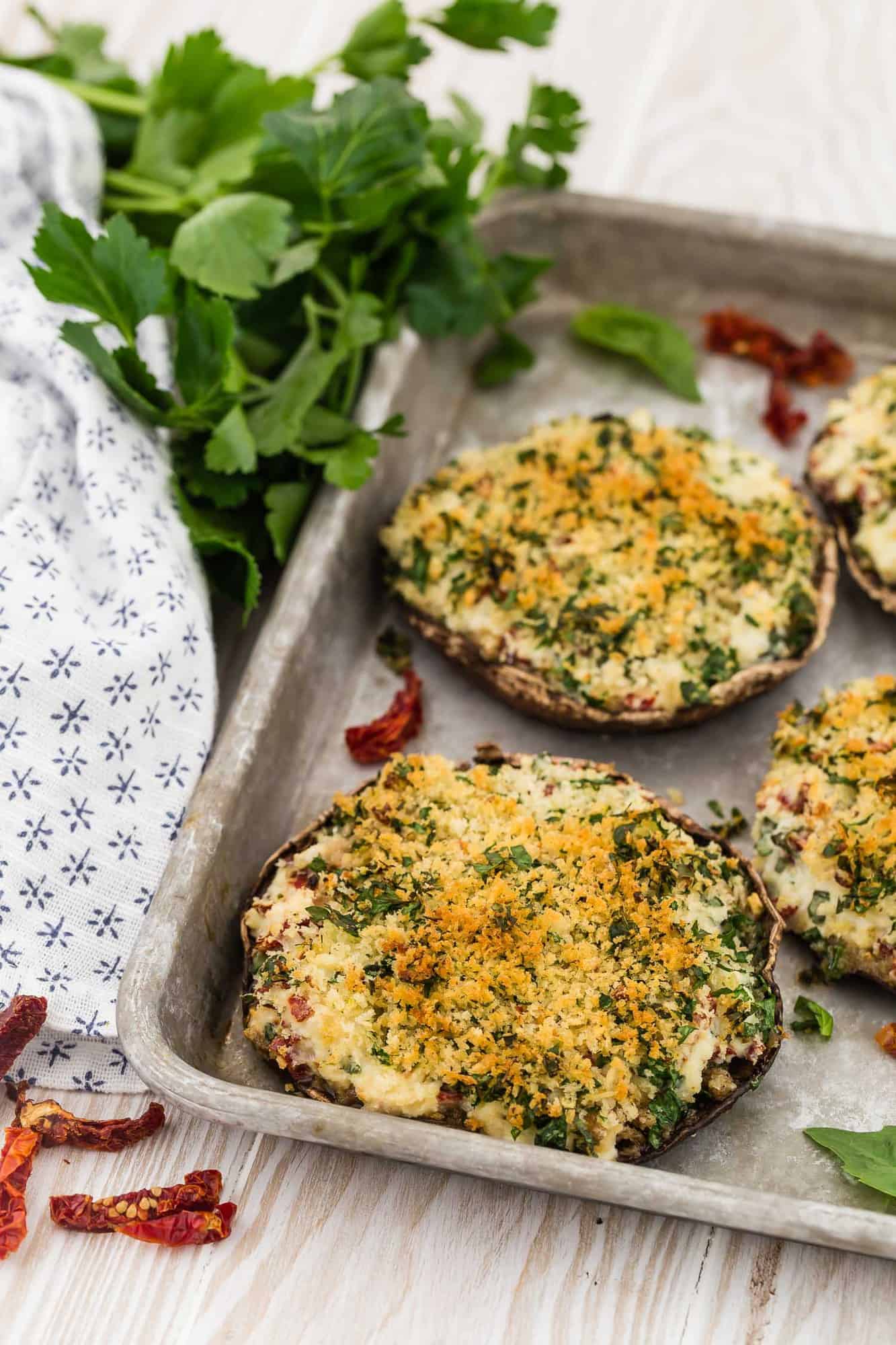 Stuffed mushrooms on a metal baking sheet, with parsley in background.