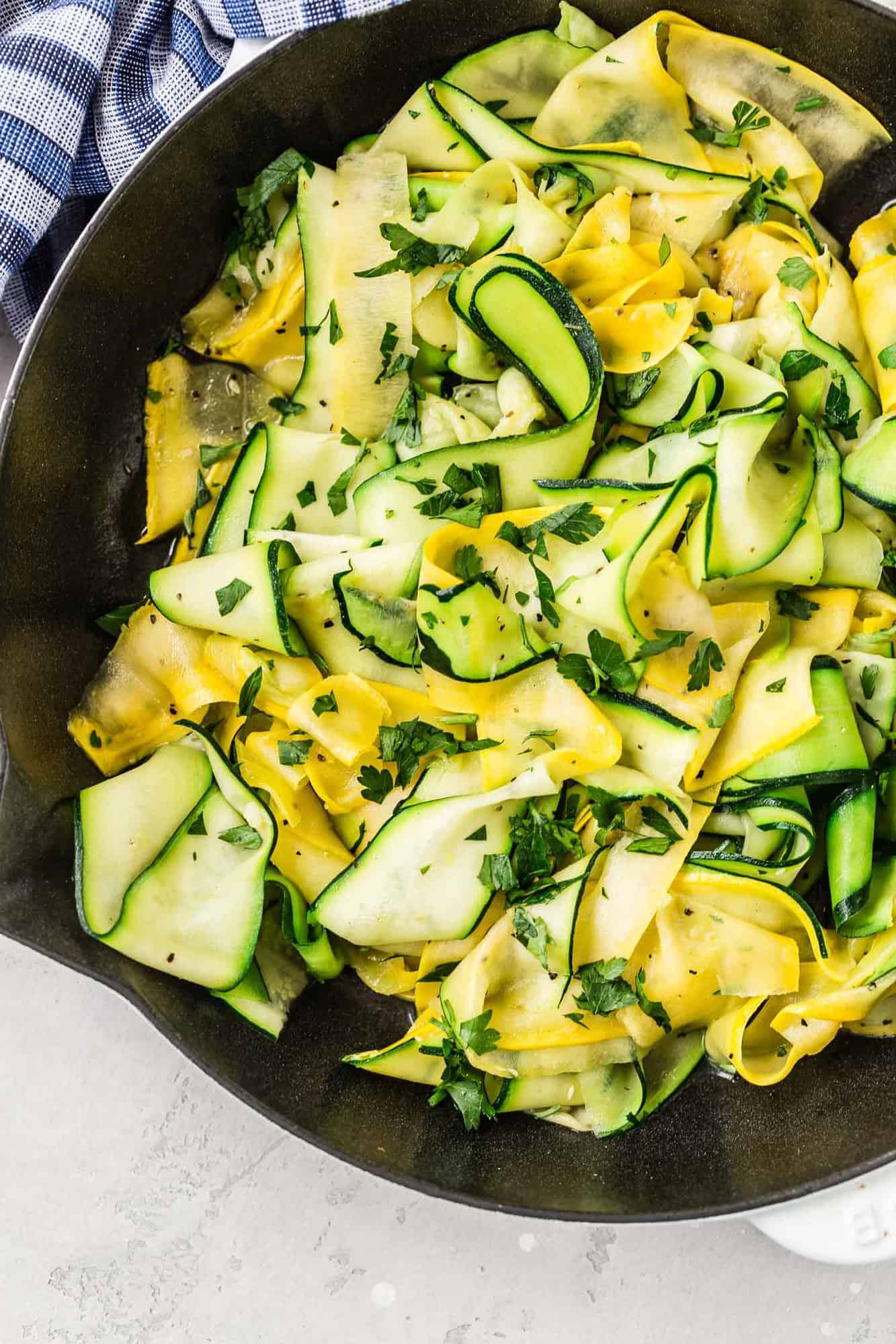 Yellow and green squash and zucchini ribbons in a skillet.