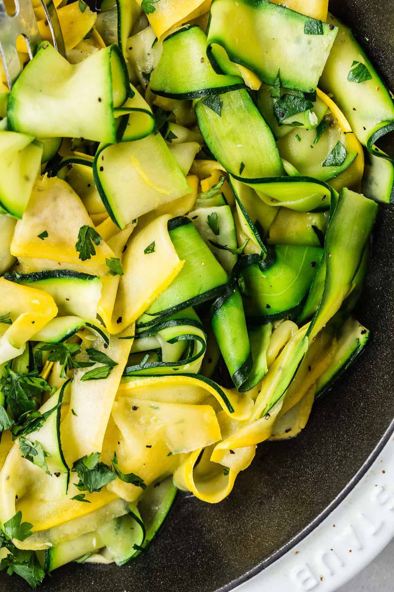 Overhead view of summer squash and zucchini noodles in a skillet.