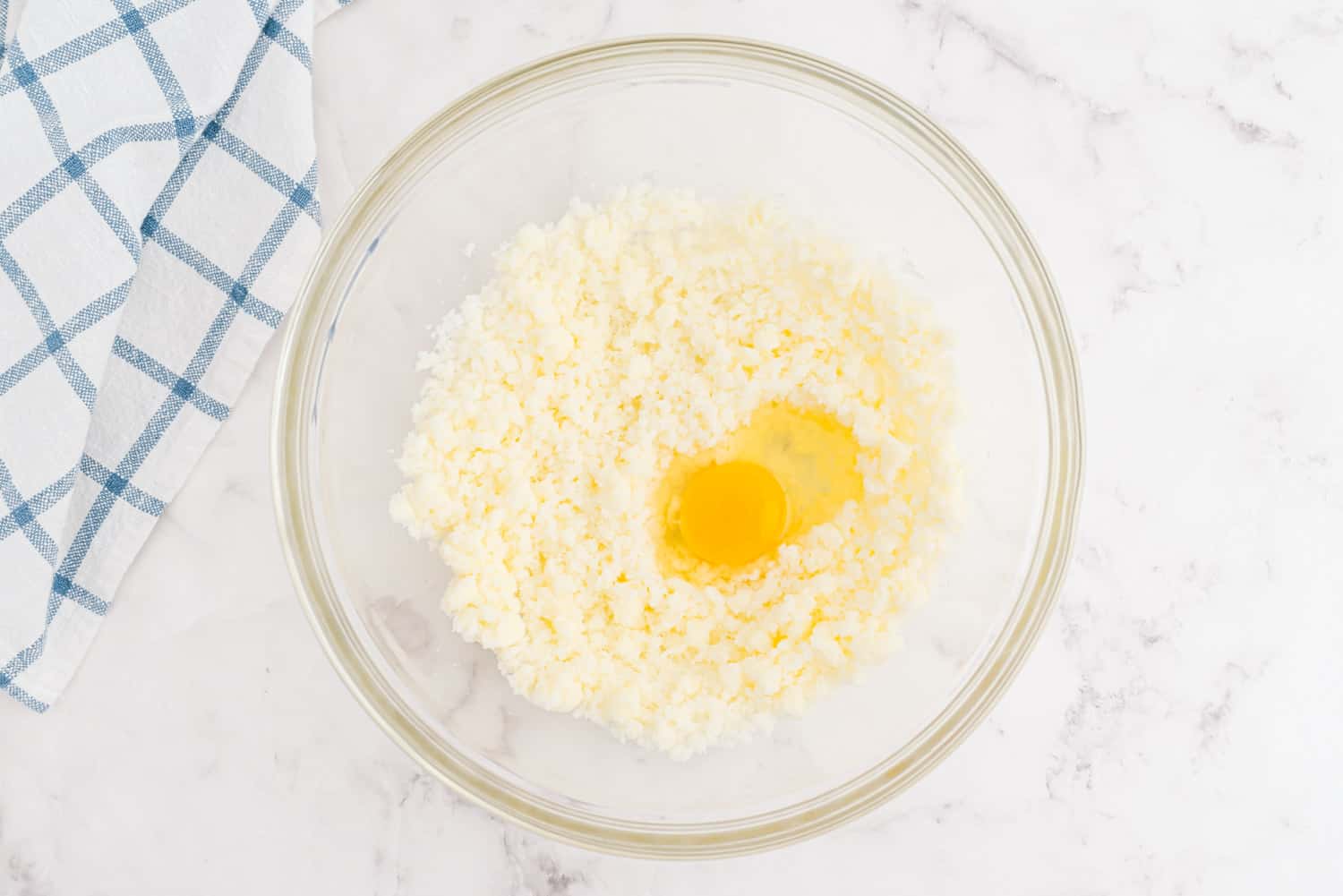 Butter, sugar, eggs, in a clear glass mixing bowl.