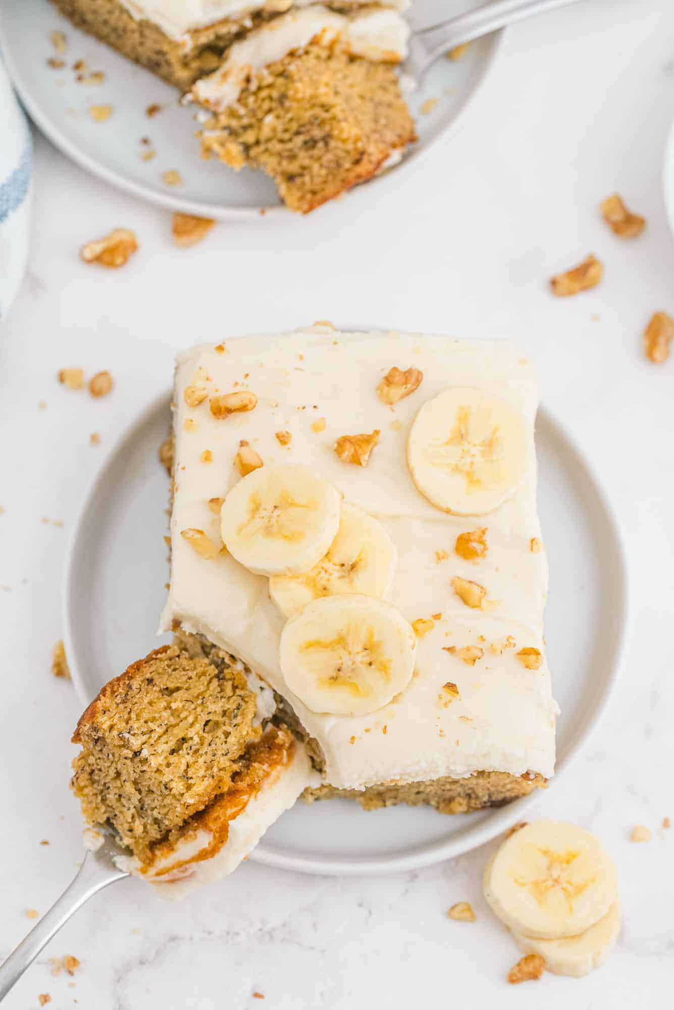 Overhead view of frosted cake on a plate, one bite off to the side.