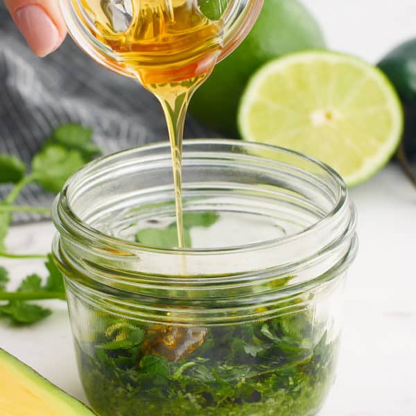 Honey being poured into salad dressing jar.