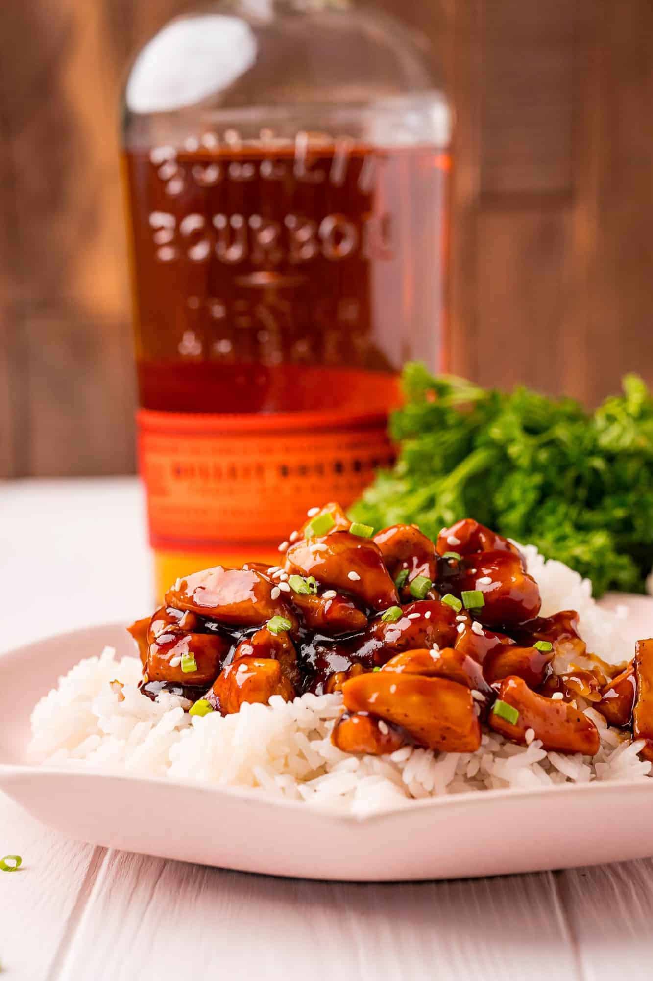 Plated chicken with a bottle of bourbon in the background.