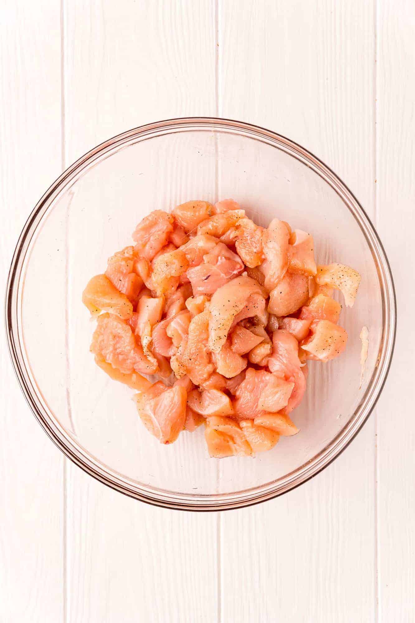 Chicken cut into small pieces in a clear glass bowl.