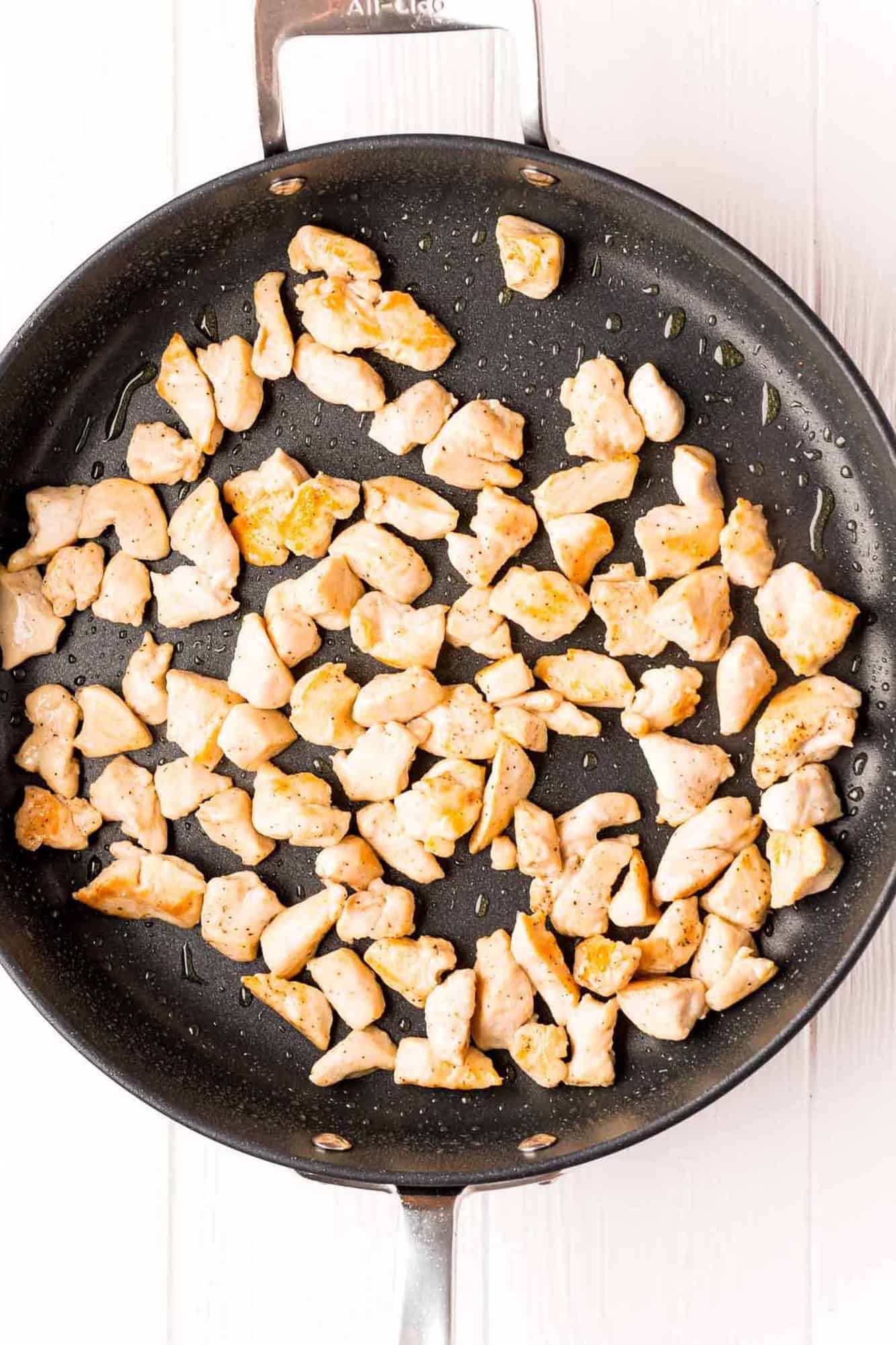 Cooked chicken pieces in a large black skillet.