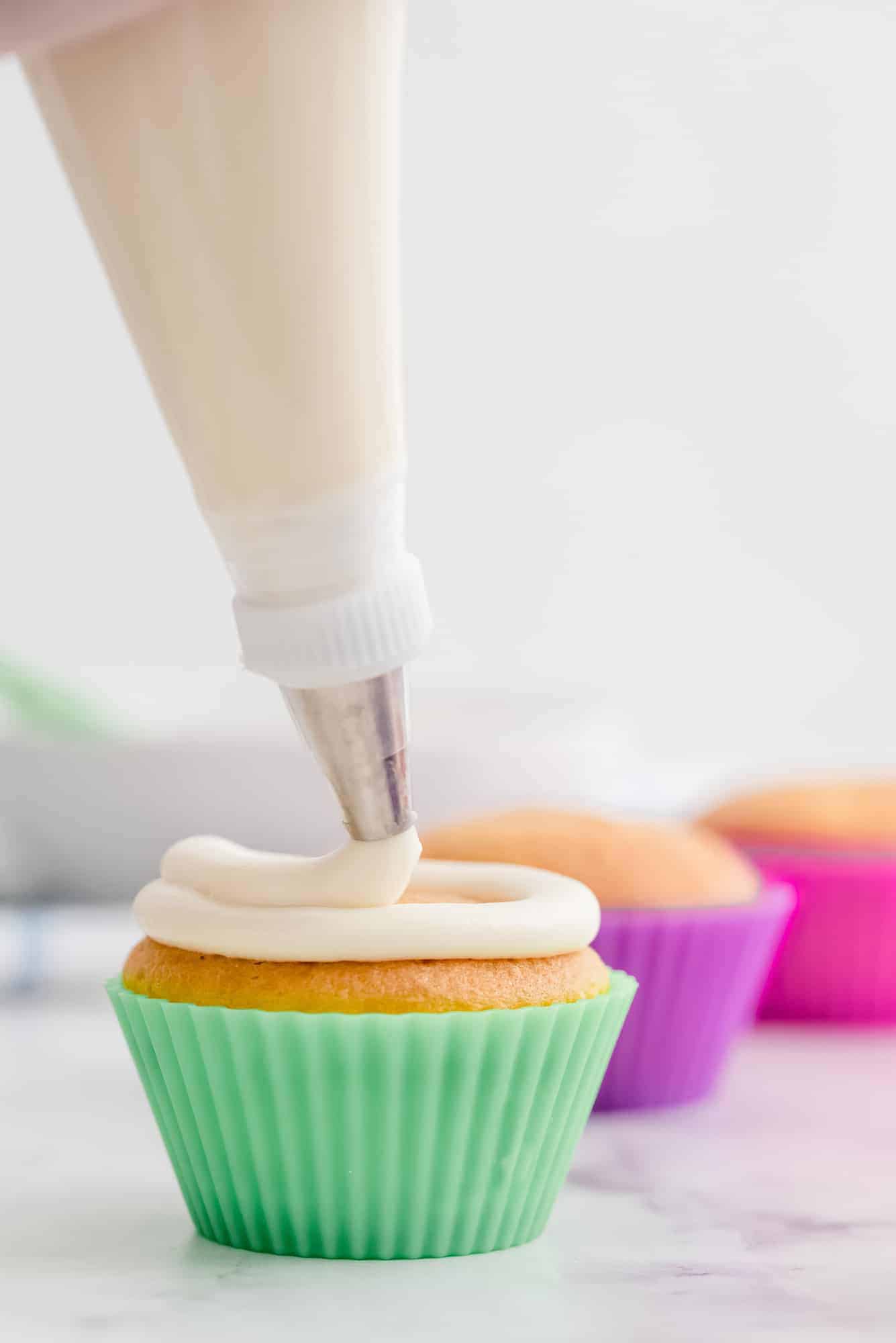 Frosting being piped onto cupcakes.