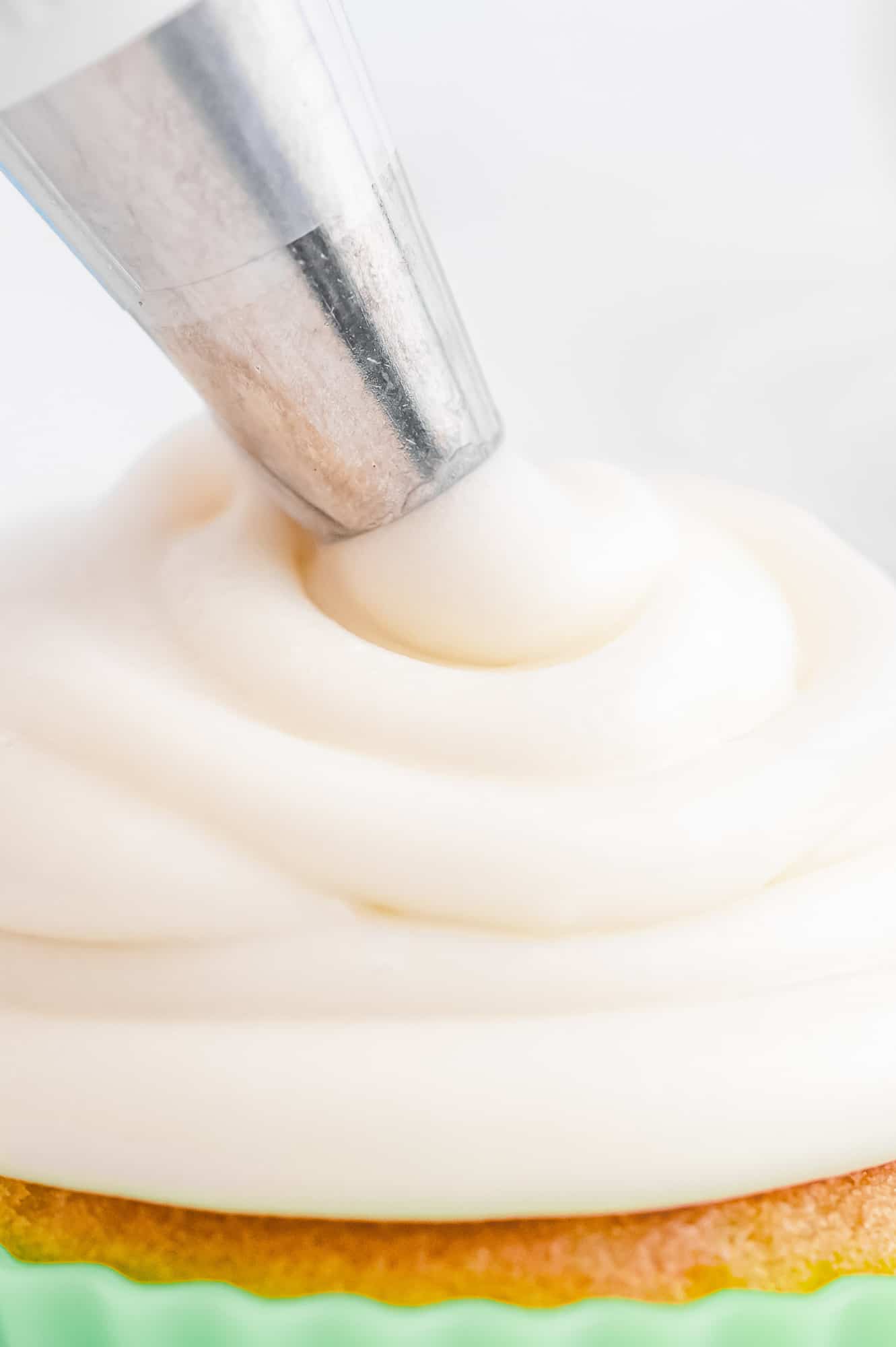 Close up of frosting being piped on a cupcake.