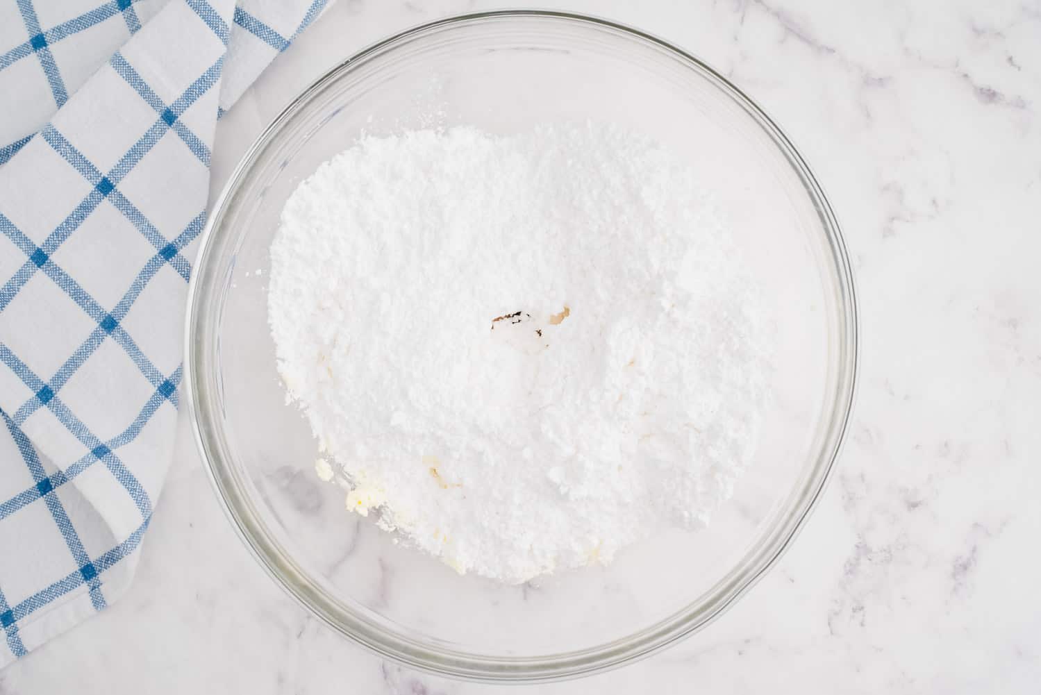 Bowl with powdered sugar and vanilla extract visible in it.