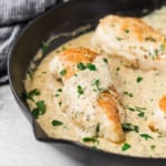 Chicken breast in a black pan with creamy mustard sauce.