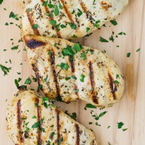 Close up view of a grilled chicken breast marinated in Italian chicken marinade. It is sprinkled with chopped fresh parsley.