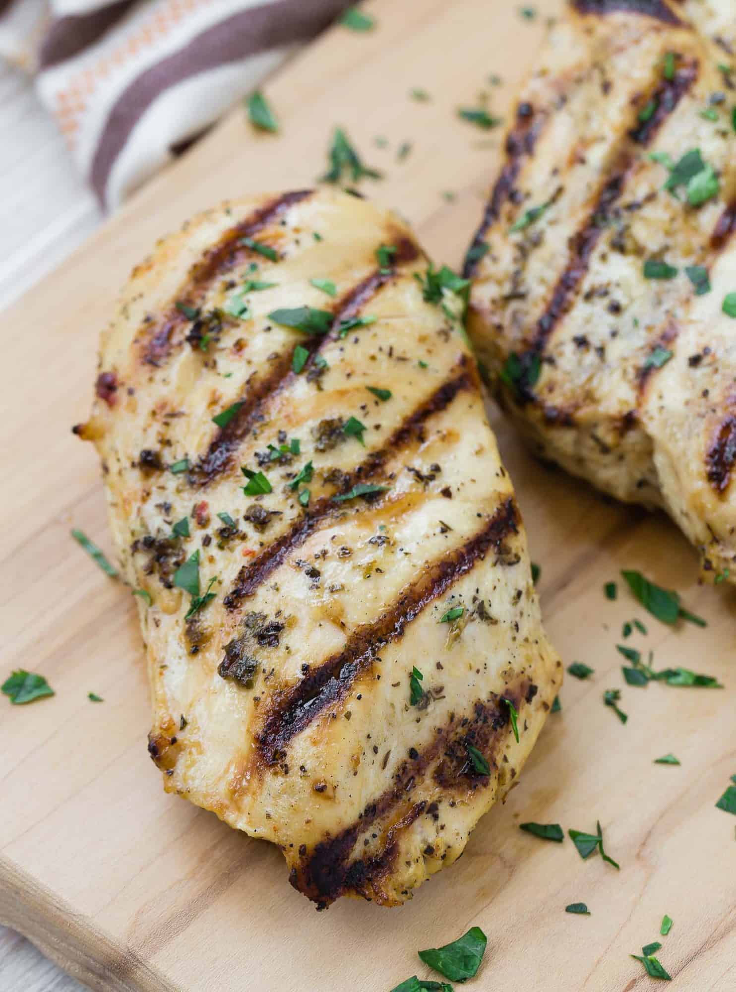 A marinated grilled chicken breast topped with chopped fresh parsley.