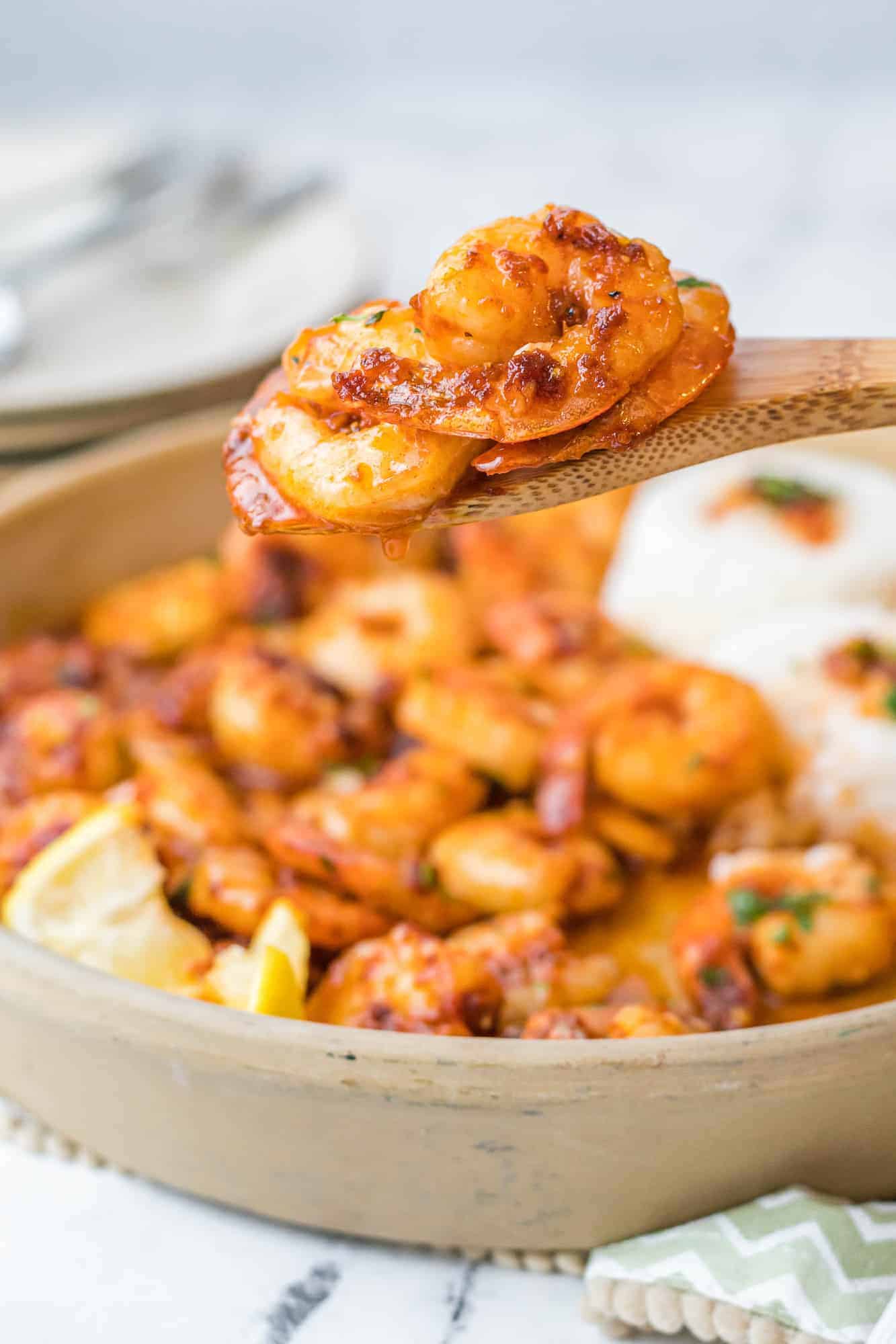 Seasoned and cooked shrimp on a serving spoon, more in the background.