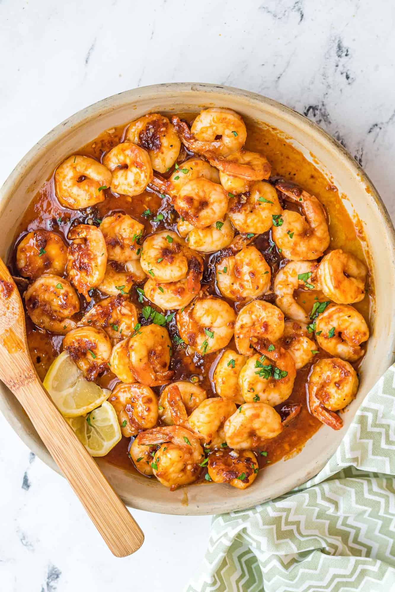 Cooked seasoned shrimp in a bowl with parsley and lemon.