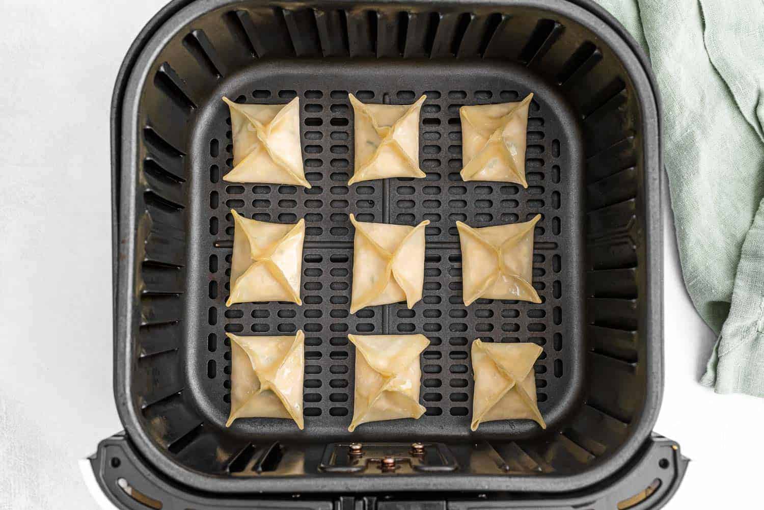 Crab rangoon in an air fryer basket.