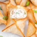 Air fryer crab rangoons, one split open to show filling.