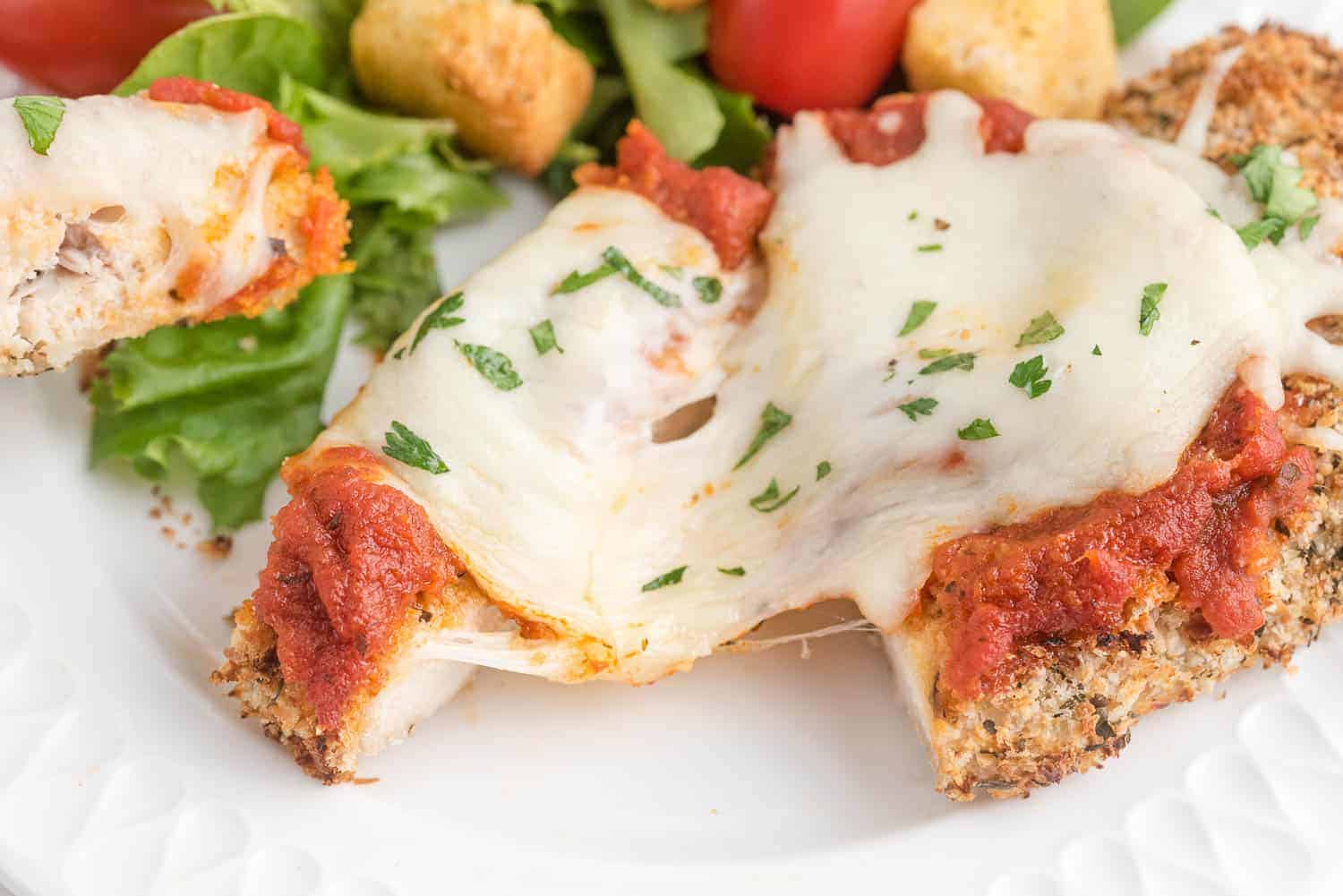 Close up of chicken topped with melted mozzarella cheese.