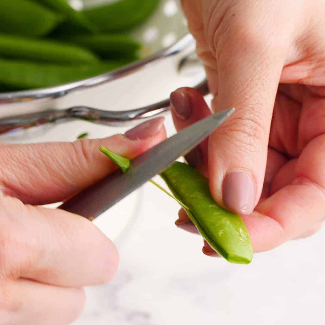 String being removed from a sugar snap pea.