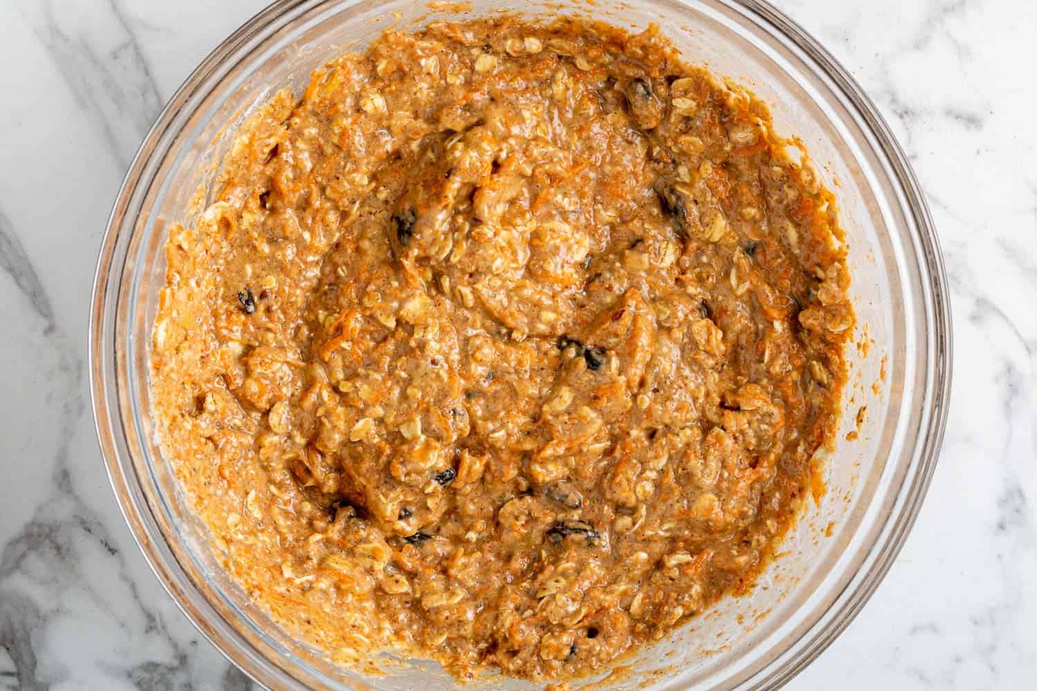 Muffin batter in a clear glass mixing bowl.