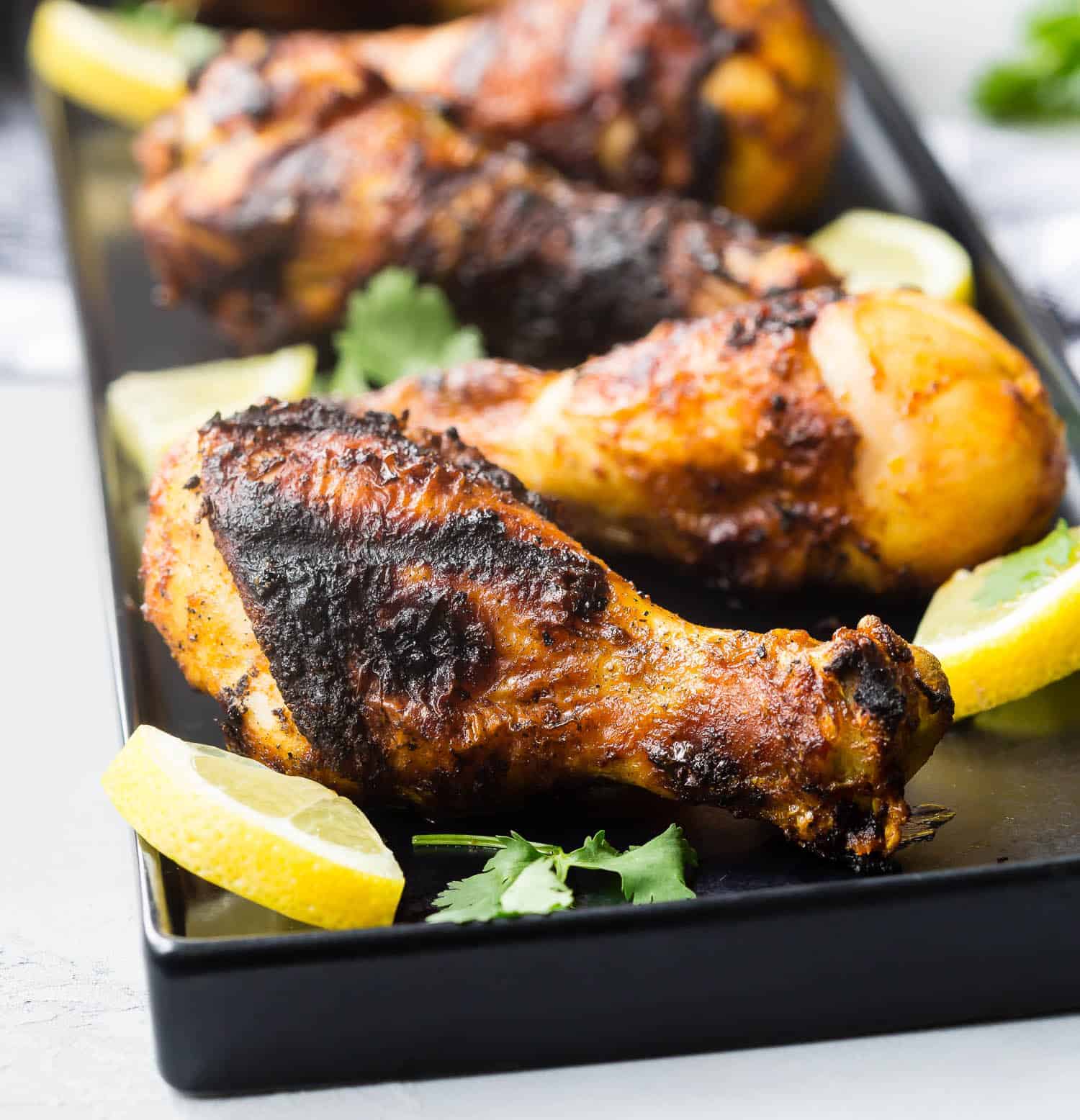 Drumsticks on a black platter with lemons.