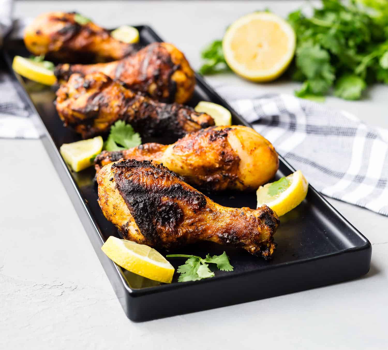 Grilled drumsticks on a long, thin black platter.